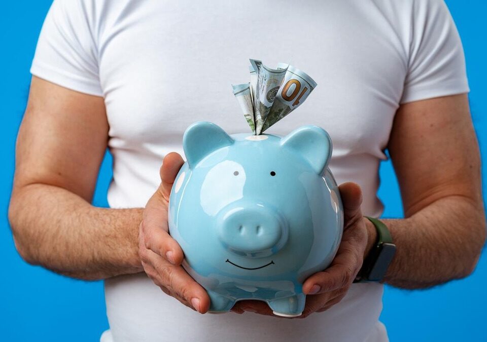 Man holding blue piggy bank with dollar bills sticking out, symbolizing investment savings and financial loss